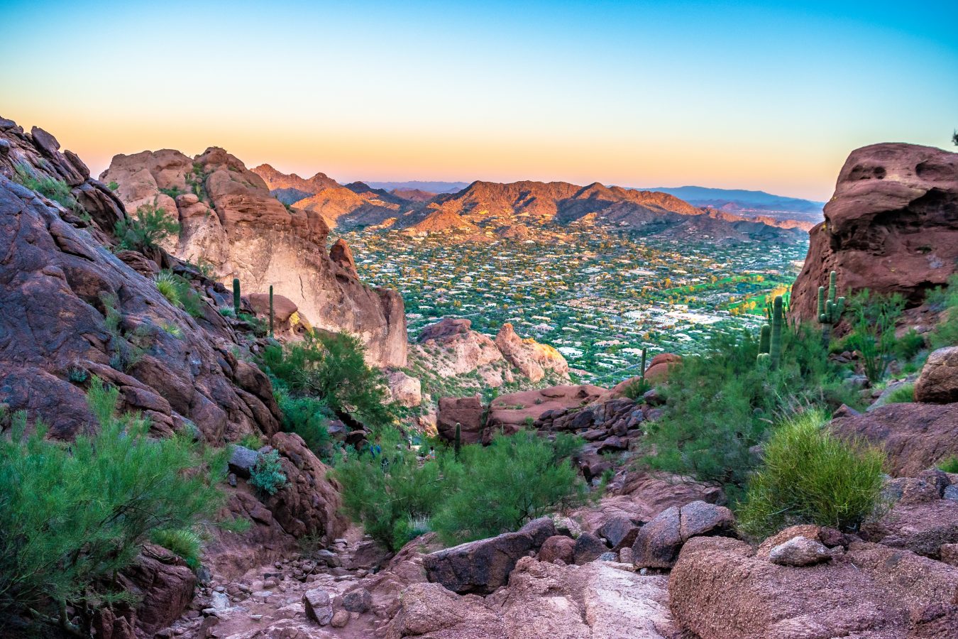Phoenix is one of the cheapest summer destinations for 2023. Mountains and desert foliage in the foreground is neighborhood streets in the valley below.