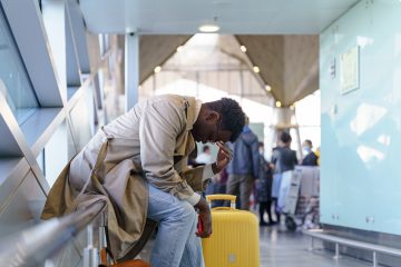 Black young man upset and tired in the airport because he has jet lag.