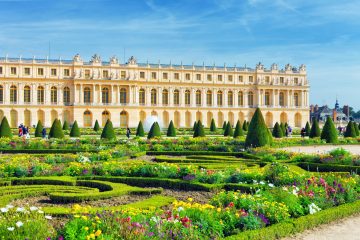 Pond in front of the Royal residence at Versailles near Paris in France in summer with flowers in bloom.