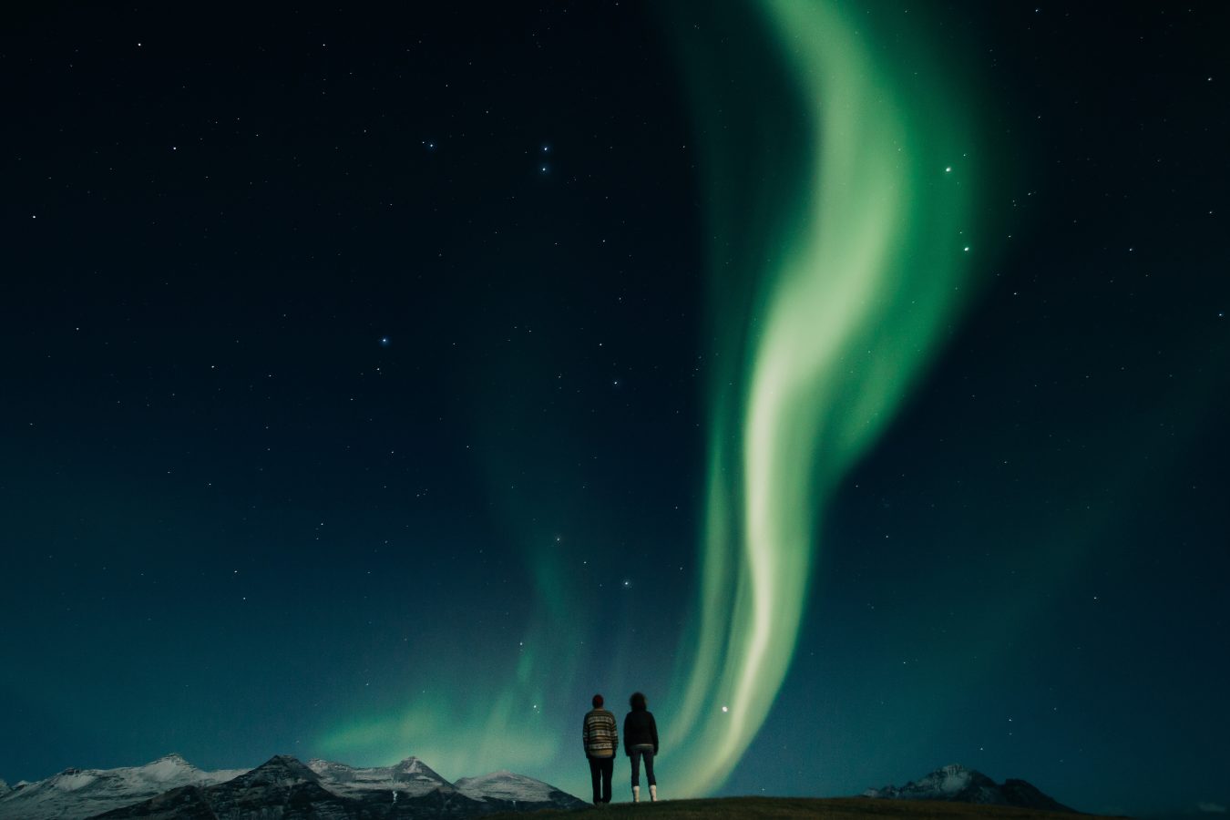 Two travelers watching the northern lights in Iceland during spring break 2025.