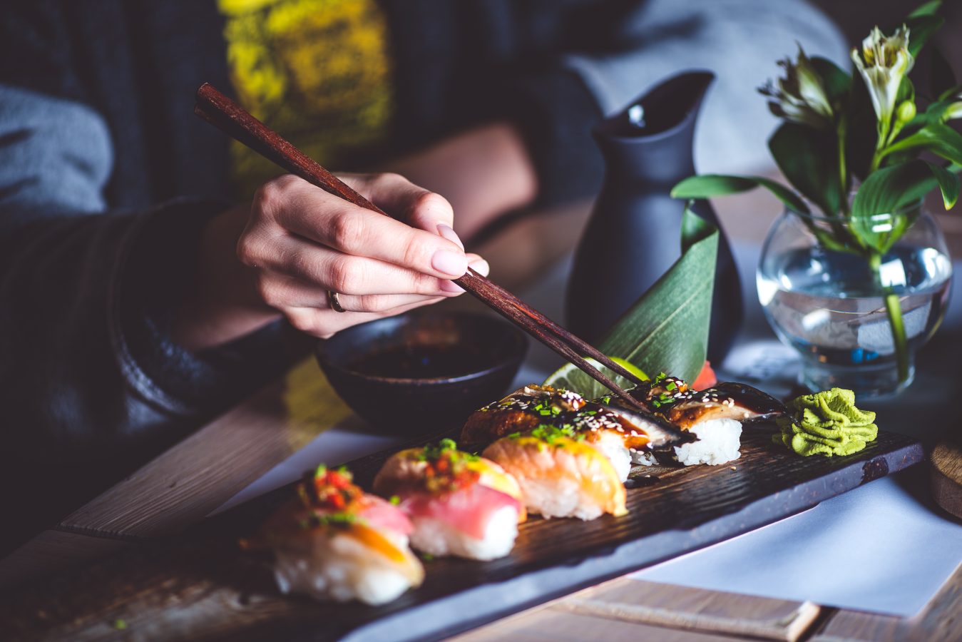 Man eating sushi set with chopsticks at a restaurant in Japan.