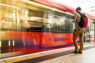 A train passes by a man in London