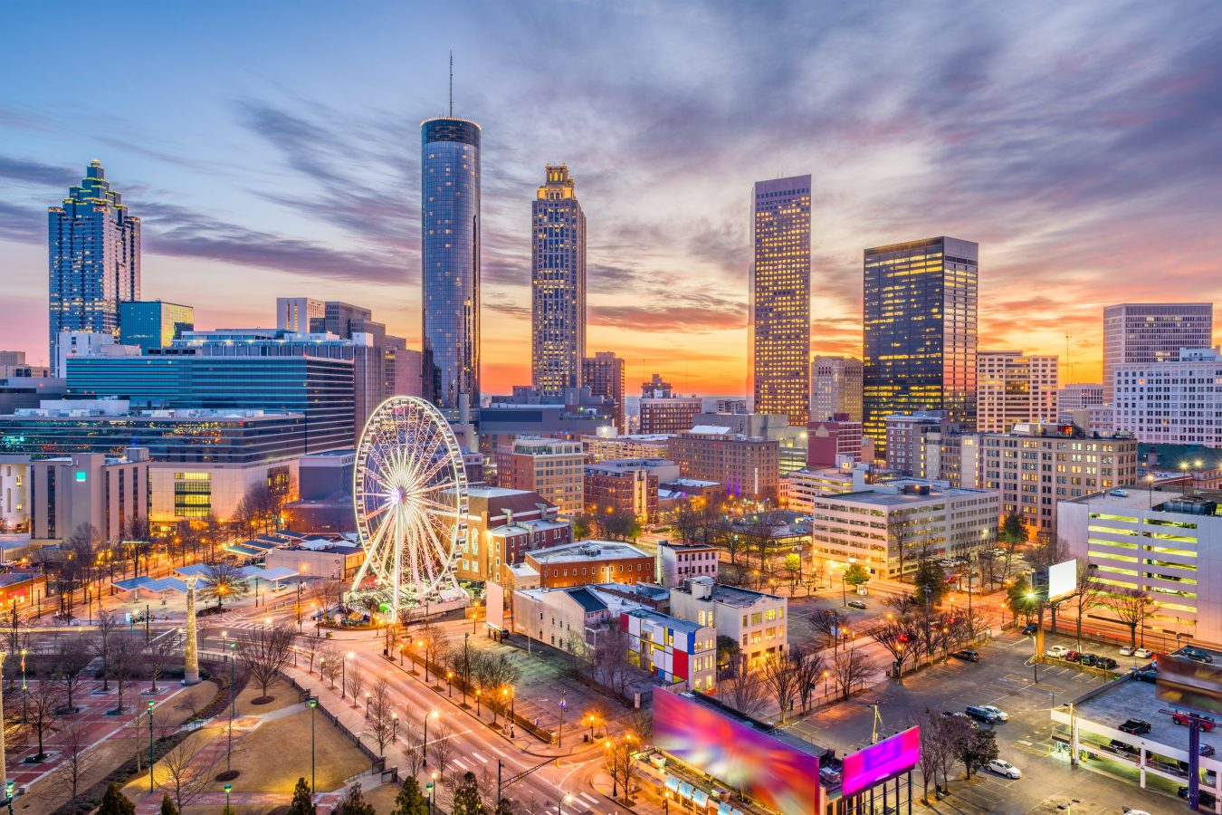 The skyline at dusk of Atlanta - a great spot for a cheap summer trips in the us. In the foreground is a ferris wheel.