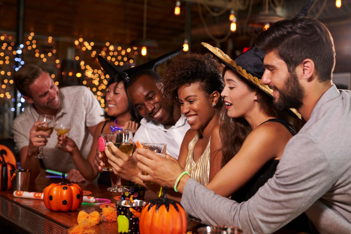 Group of friends at a Halloween party sharing drinks in a bar.