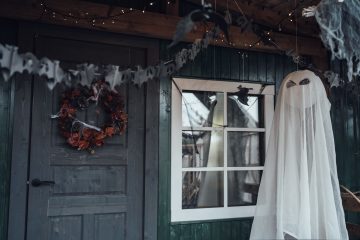 Front porch decorated for Halloween with ghost and garland.