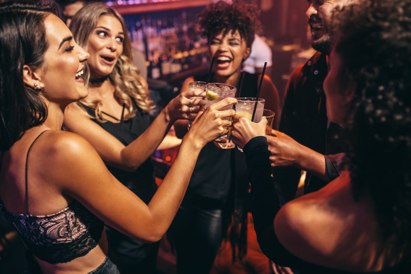 Group of friends partying in a nightclub and toasting drinks.