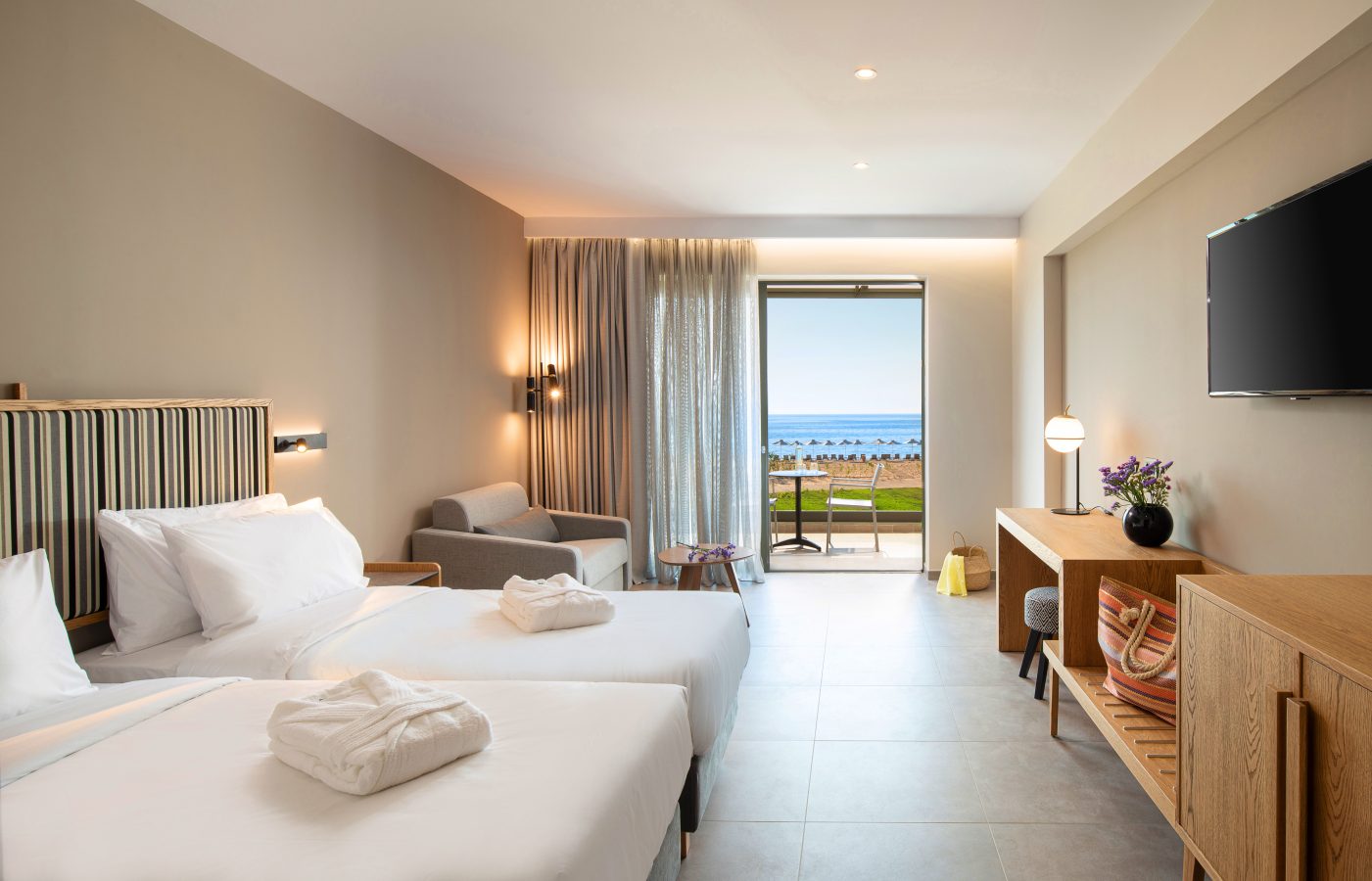 White and clean hotel room prepped for guests with towels folded on the beds.