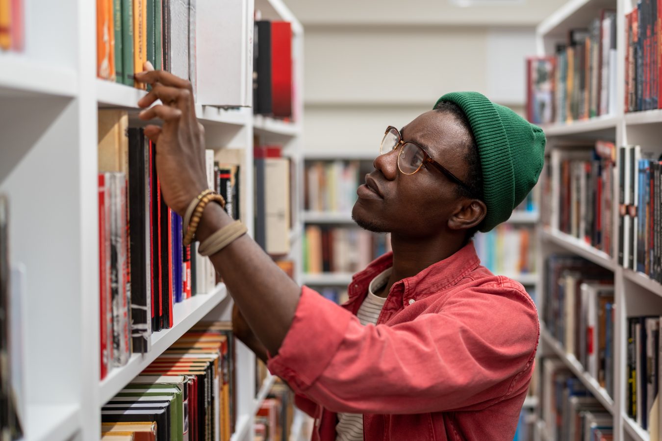 Young guy looking through library stacks.