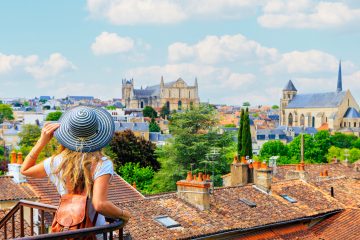 Woman on a solo student travel trip overlooking Poitiers cityscape from a balcony in France.