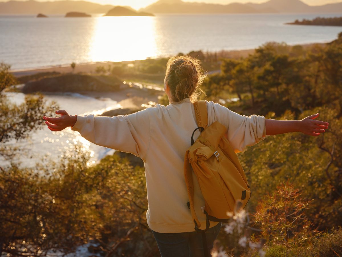 Young adult traveler overlooking the sunset on the water in the mountains in Fethiye, Turkey while on a solo student travel trip.