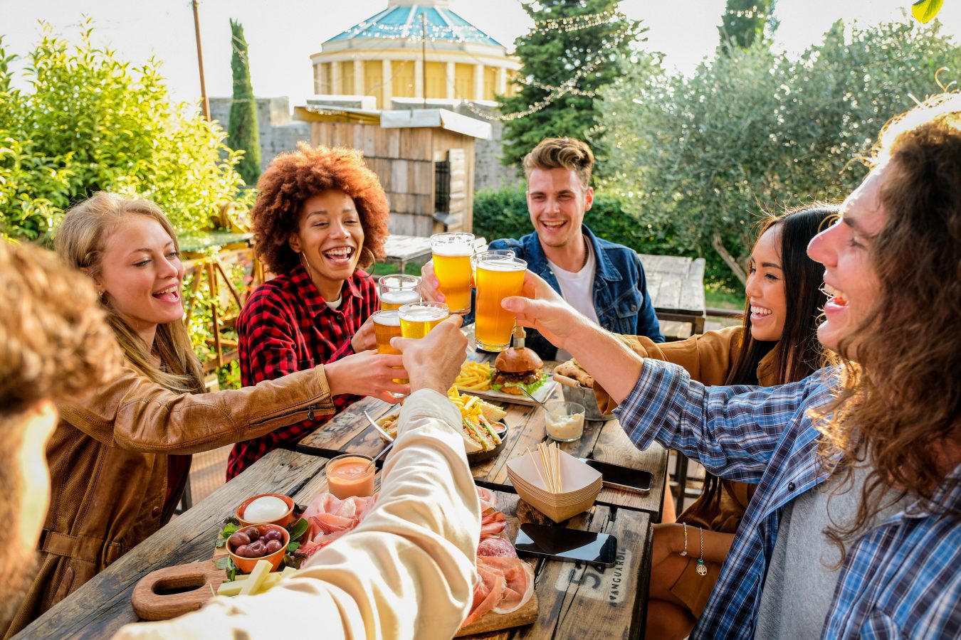 Group of friends gathered at an outdoor pub restaurant, enjoying drinks during happy hour at bar.