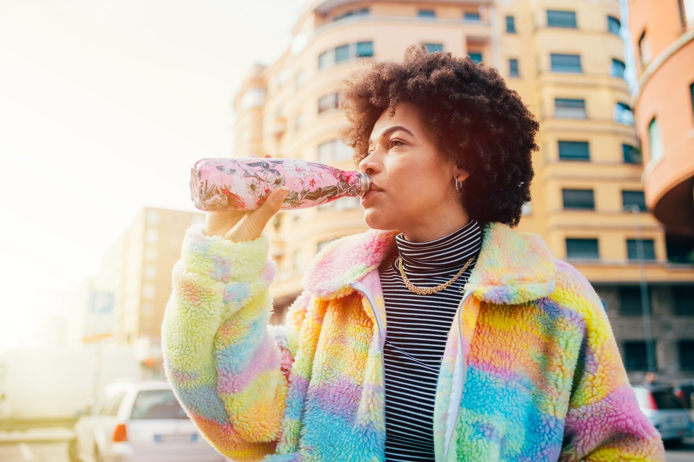 A traveler drinks from their reusable water bottle on the go, so that they can save money on eating while traveling on their student budget.