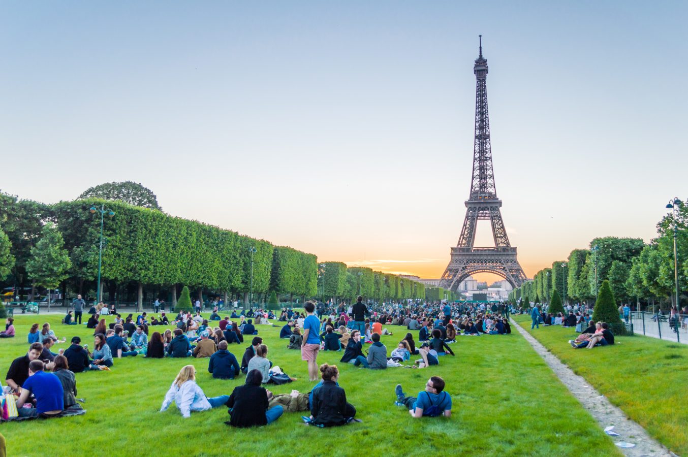 Eiffel Tower and people sitting on the grass watching sunset in Paris, France.