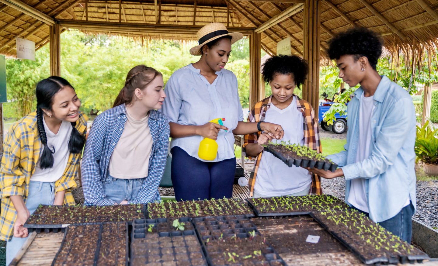 Group of students volunteering and helping in a garden to plant new plants, having learned about how they can impact their world via the many cultural benefits of student travel.