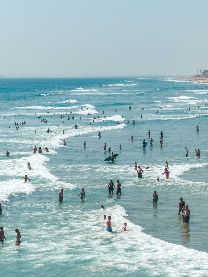 Bright blue ocean water on a sunny day at the beach with lots of people in the water