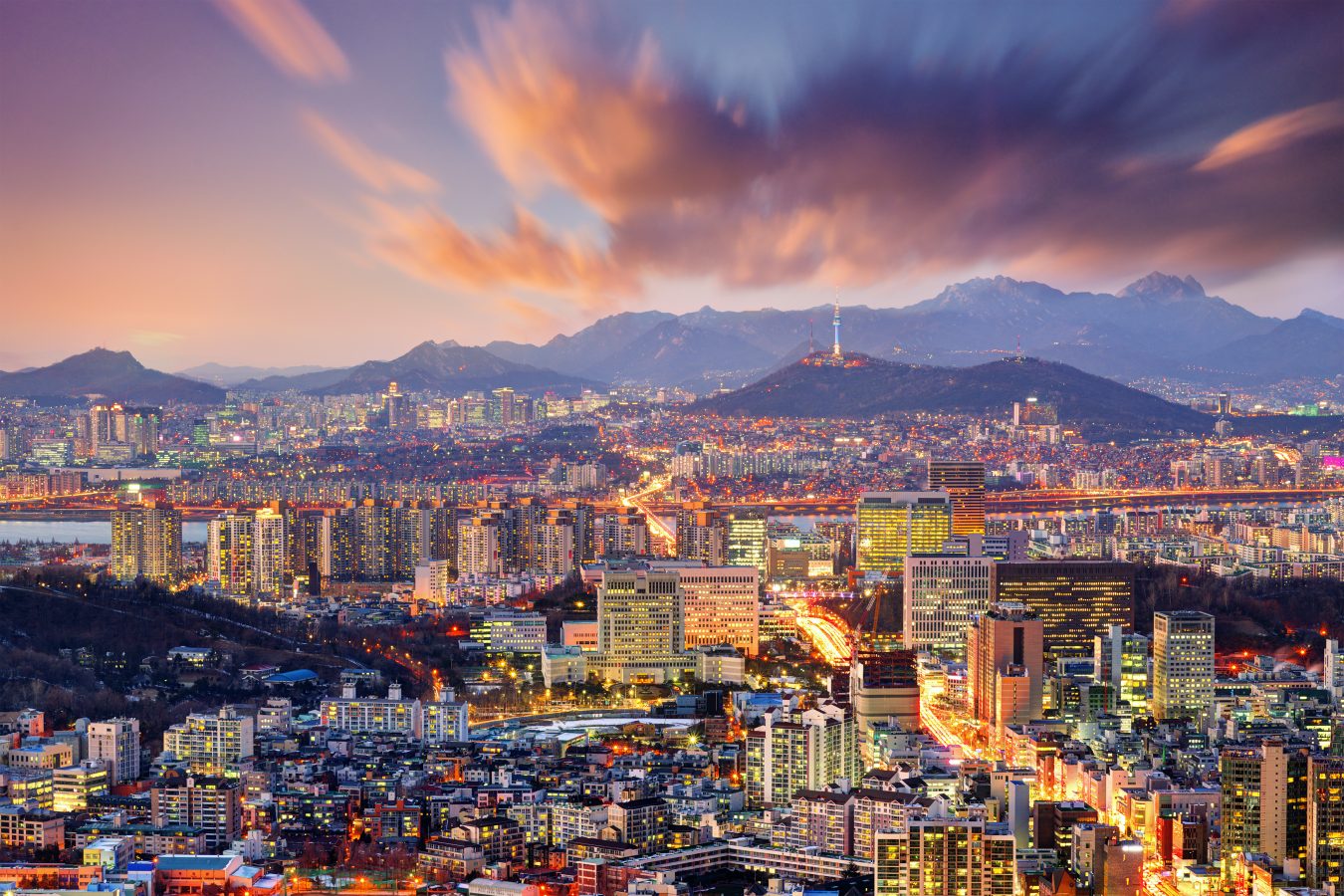 Aerial view of downtown Seoul, South Korea during sunset with mountains in the background.