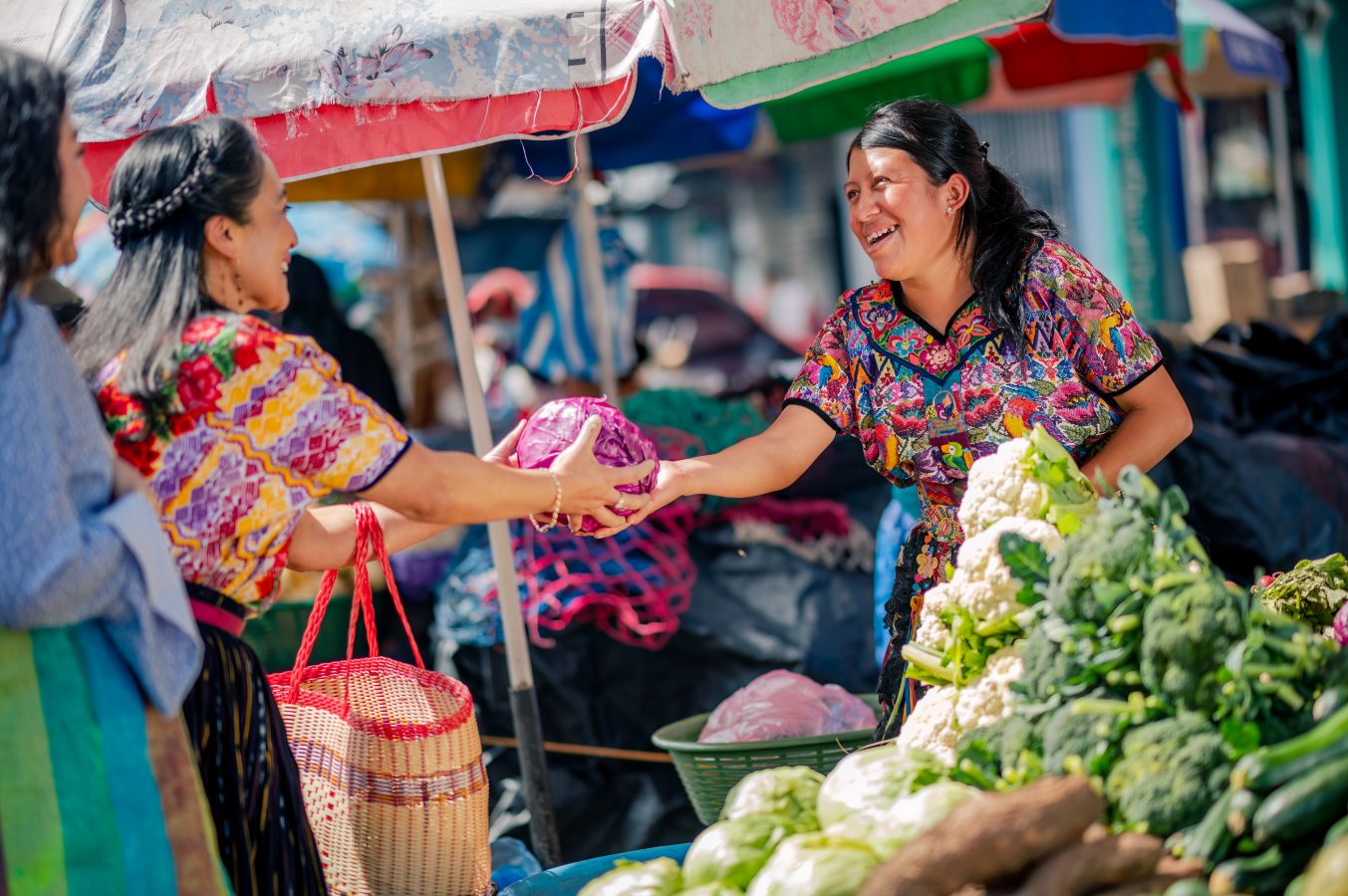 Happy vendor at a market in Quetzaltenango, Guatamala in Latin America serves her customer some fresh produce.