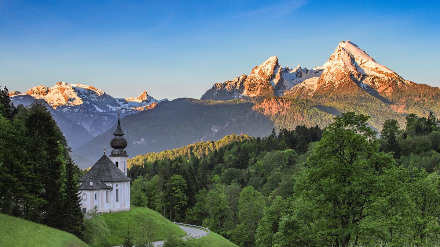 Panoramic view of Maria Gern church in Germany with snow-capped summit of Watzmann mountain. The Bavarian Alps are known for being a famous halloween movie locations for movies such as Frankenstein.