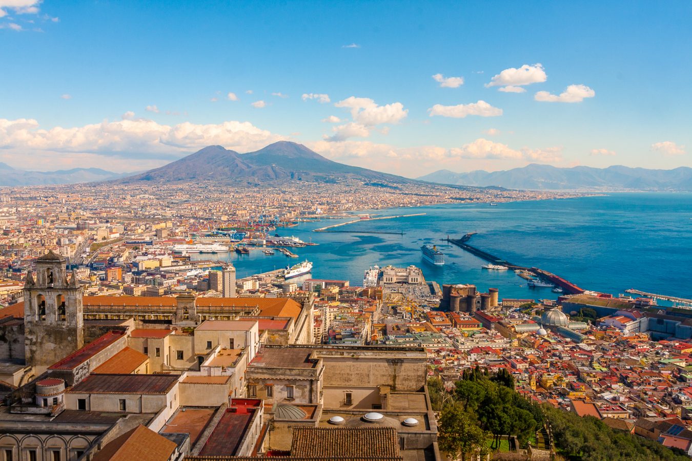 An aerial view of the city of Naples, with Mount Vesuvius in the background.