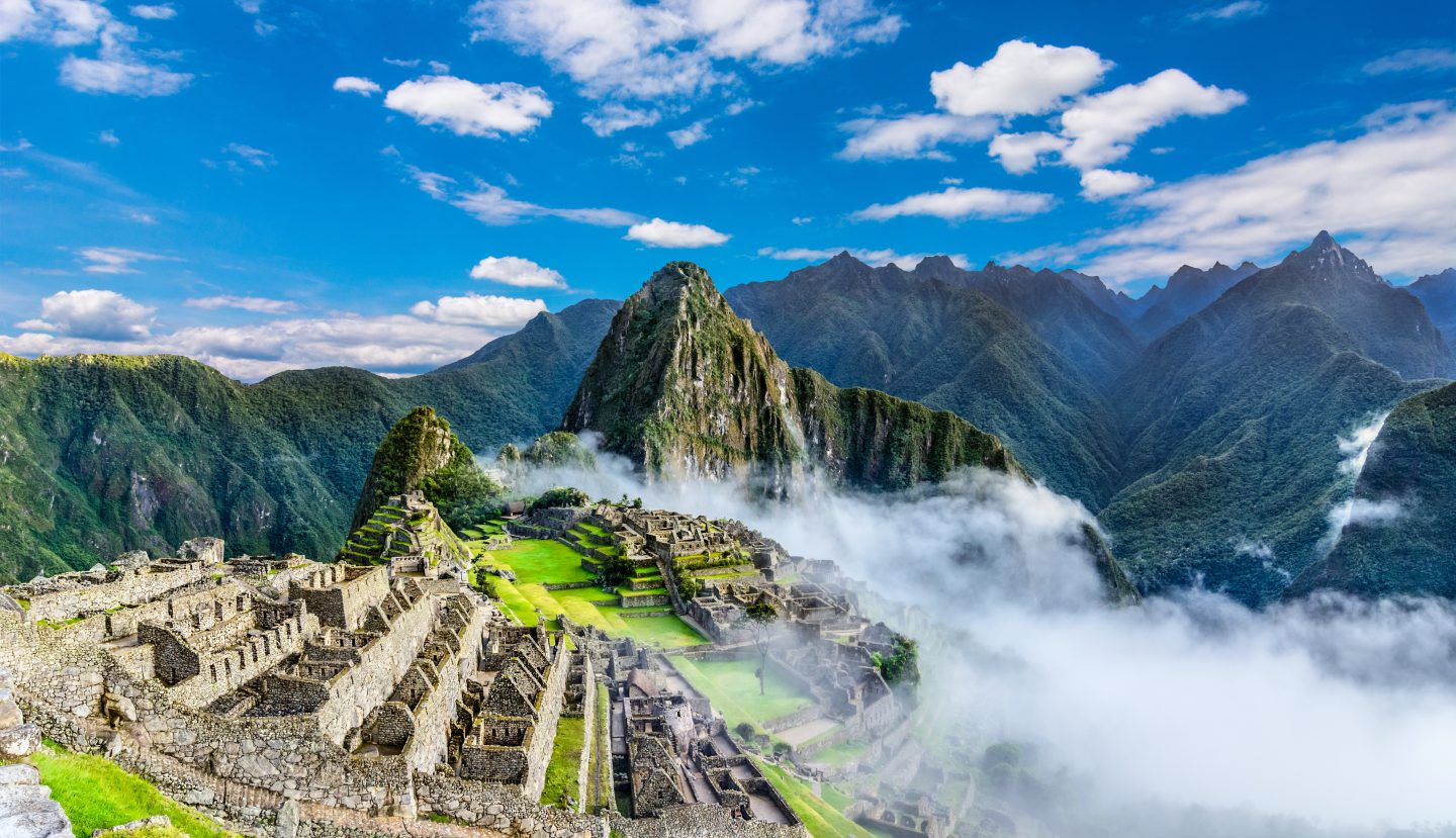 Overview of Machu Picchu, agriculture terraces, Wayna Picchu and surrounding mountains in the background.