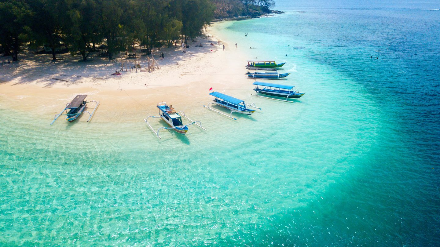 Aerial view of a private beach in Bali, Indonesia - a top trips to take in 2025 - with bright blue clear waters.